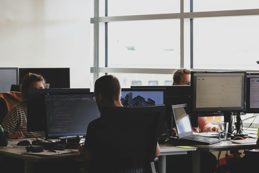 Mitarbeiter Web-End-Solutions sitzen an ihren Schreibtischen vor Monitoren